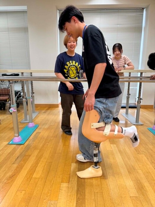 在進行物治系介紹時，目白大學物治系老師讓本校同學體驗使用義肢裝具時的行走，讓本校學生在未來課程更能同理患者的狀況並且給予適當行走訓練圖片